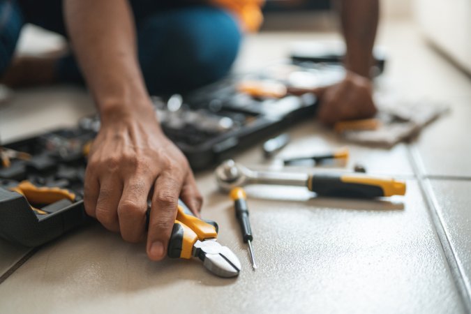 A close up of hands holding home improvement tools.