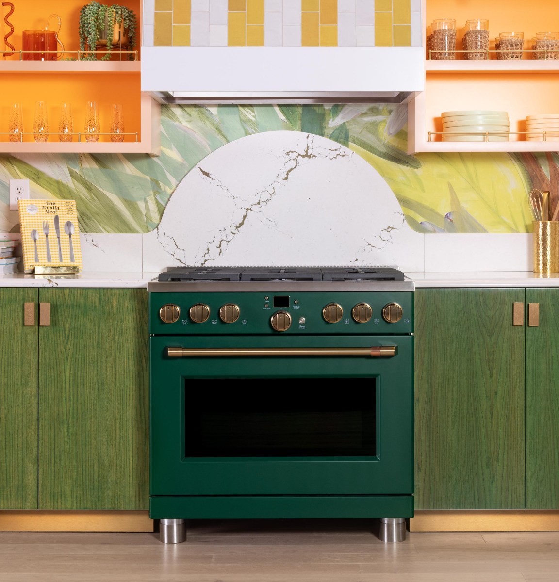 A green dual fuel range stands in a kitchen with green cabinets.