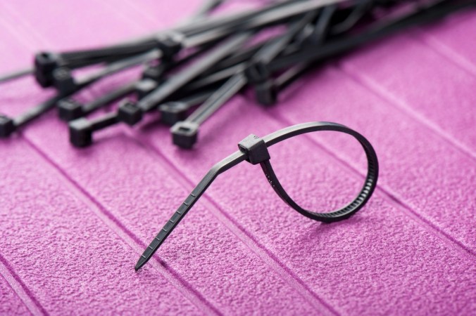 Black zip ties on a pink table.
