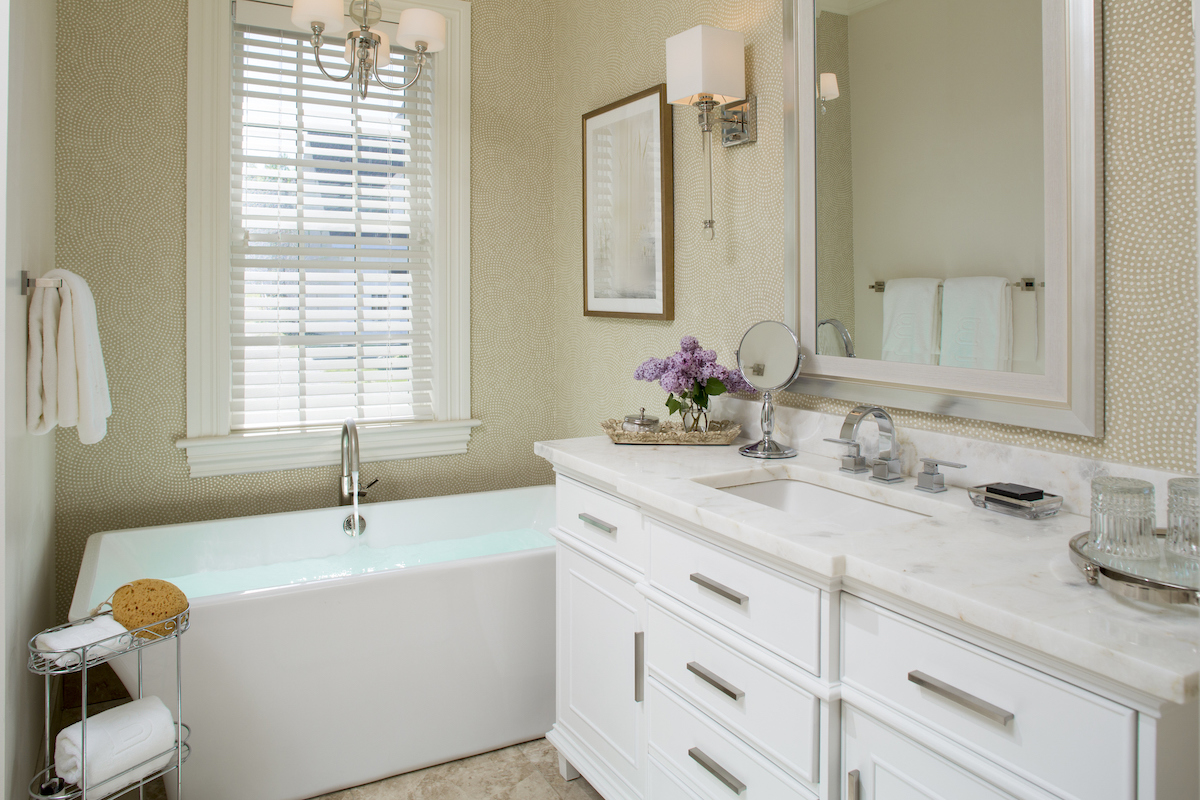 A bathroom with dotted wallpaper and a white wood vanity.