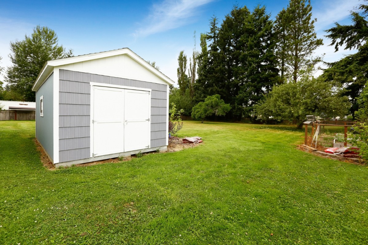 A view of a grey shed on a green lawn. 