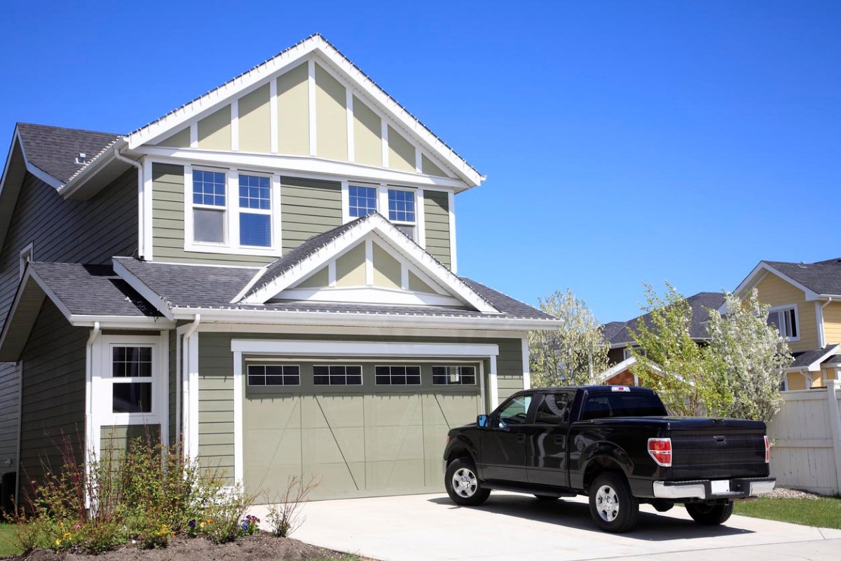 A black trucks sits in the driveway of a home. 