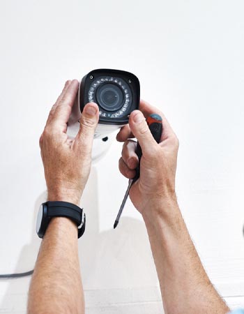 A close up of hands installing a security camera.