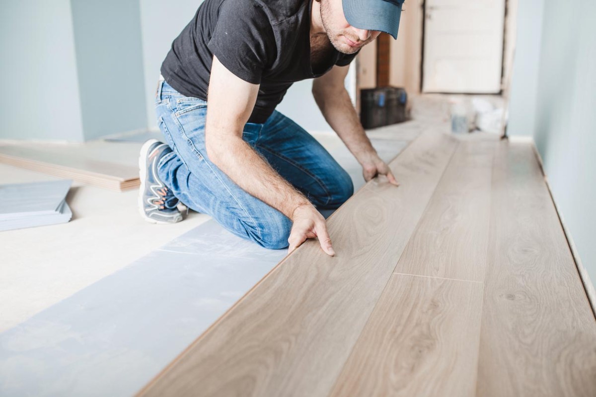 A worker installs flooring planks.