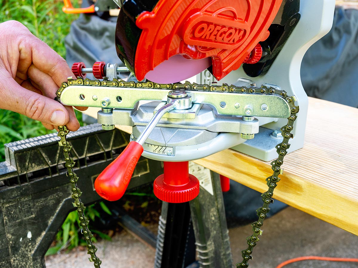 A person using the Oregon 410-120 Bench Grinder Chain Sharpener to sharpen a chainsaw chain during testing.