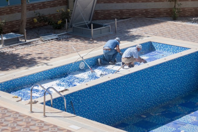 Two workers repair a pool.