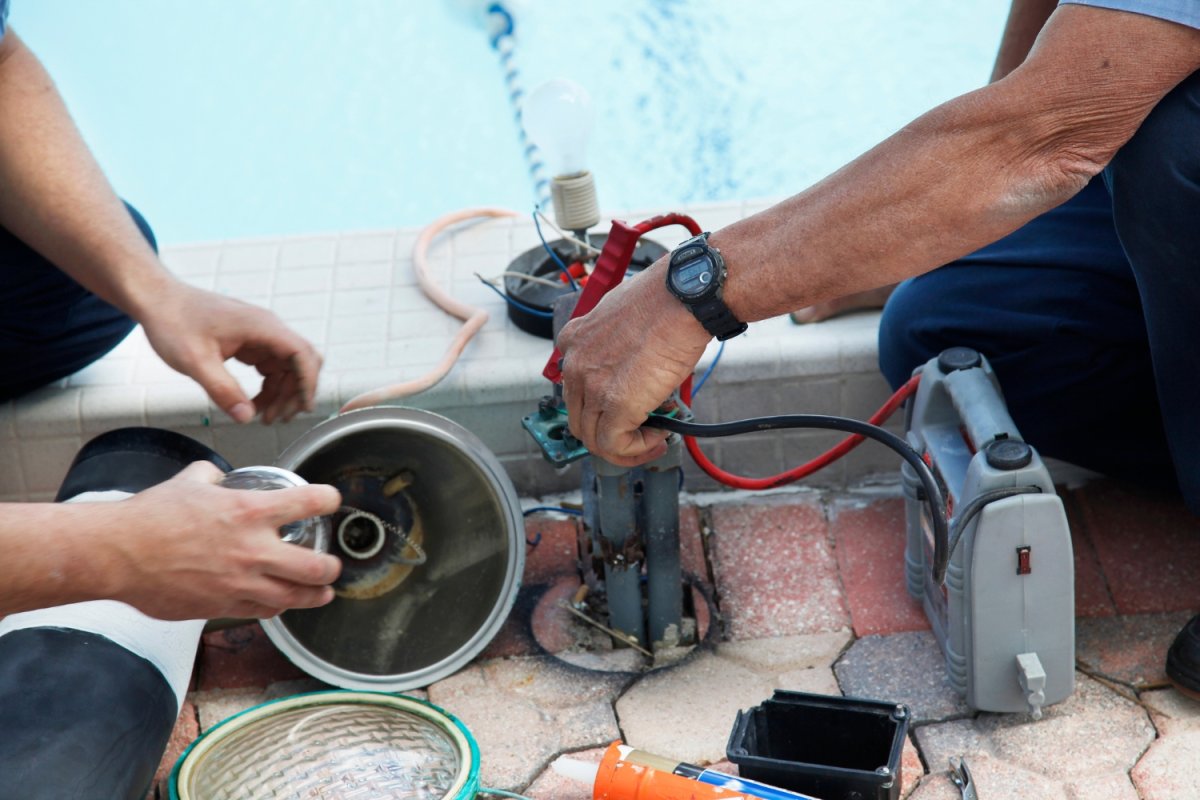 Two workers use tools to repair a pool.