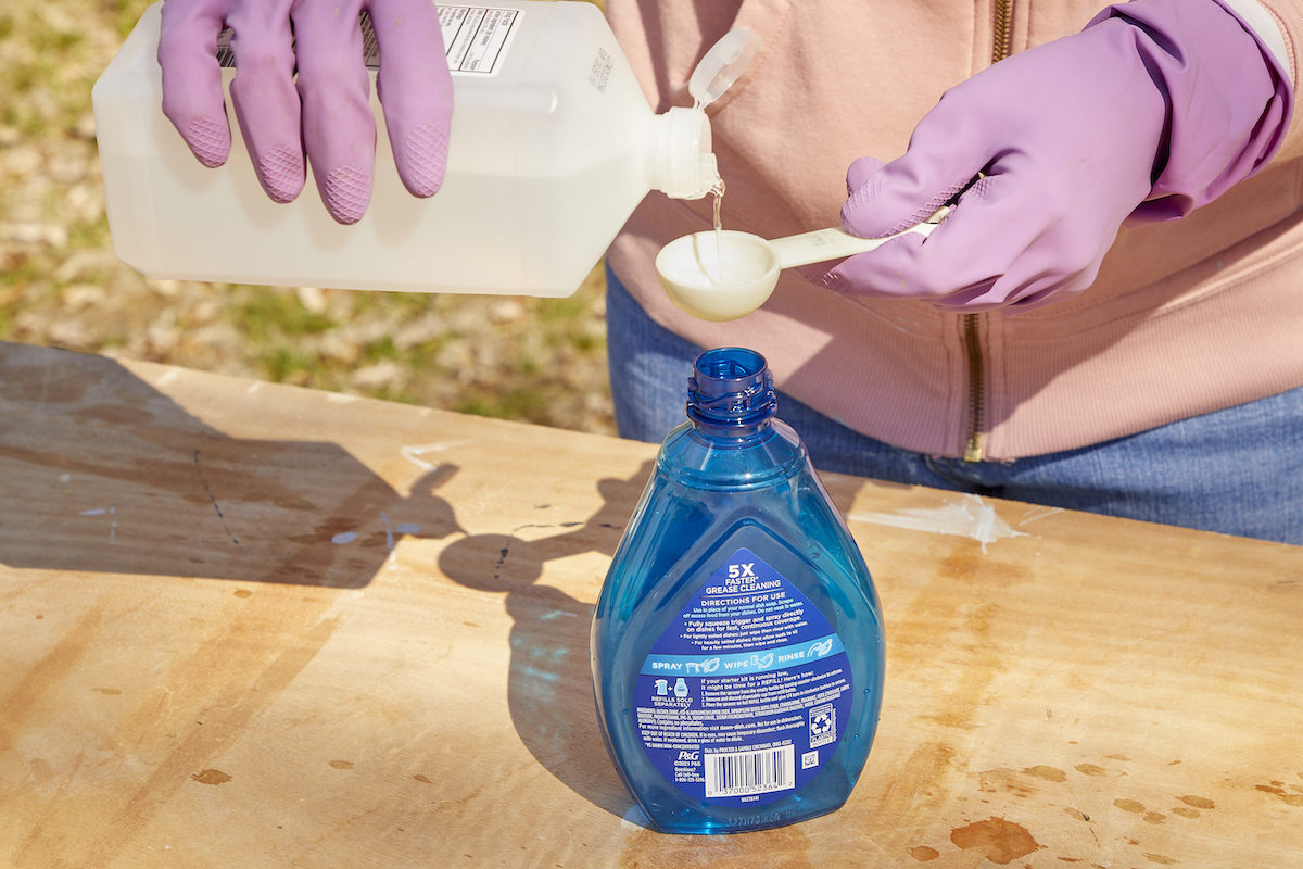 Woman measures rubbing alcohol into a Dawn Powerwash bottle.