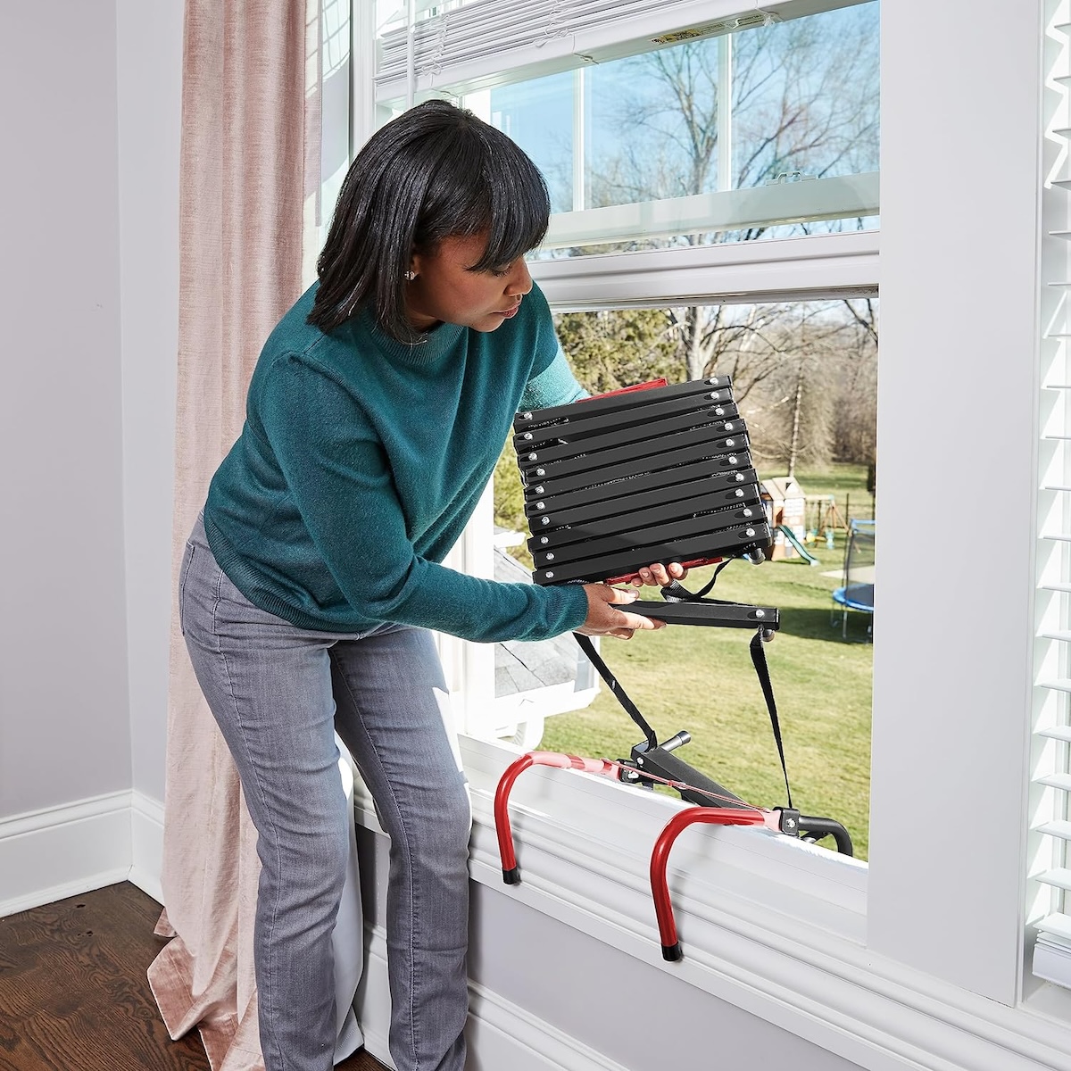 A person using a fire escape ladder out a window.