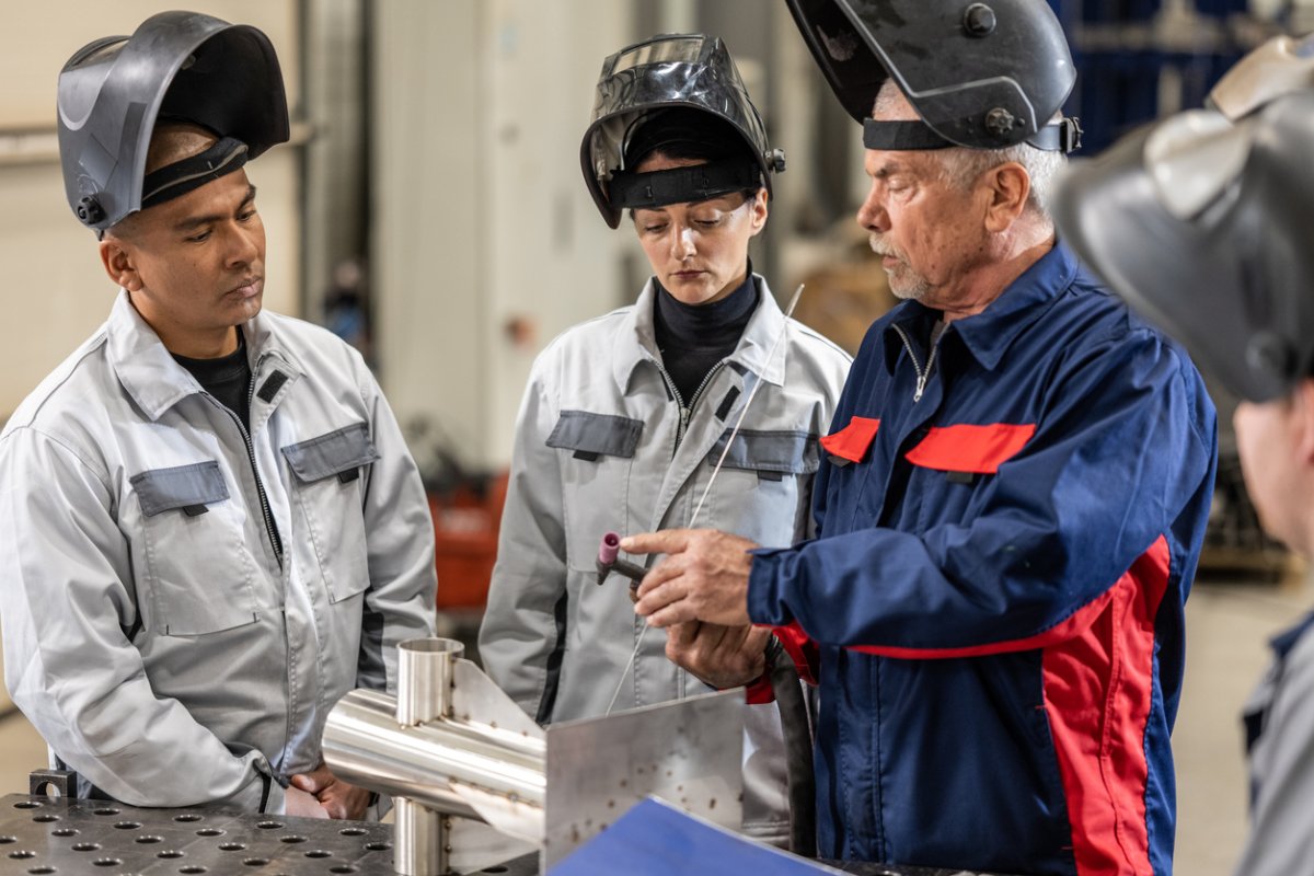 Two student welders watch an instructor. 