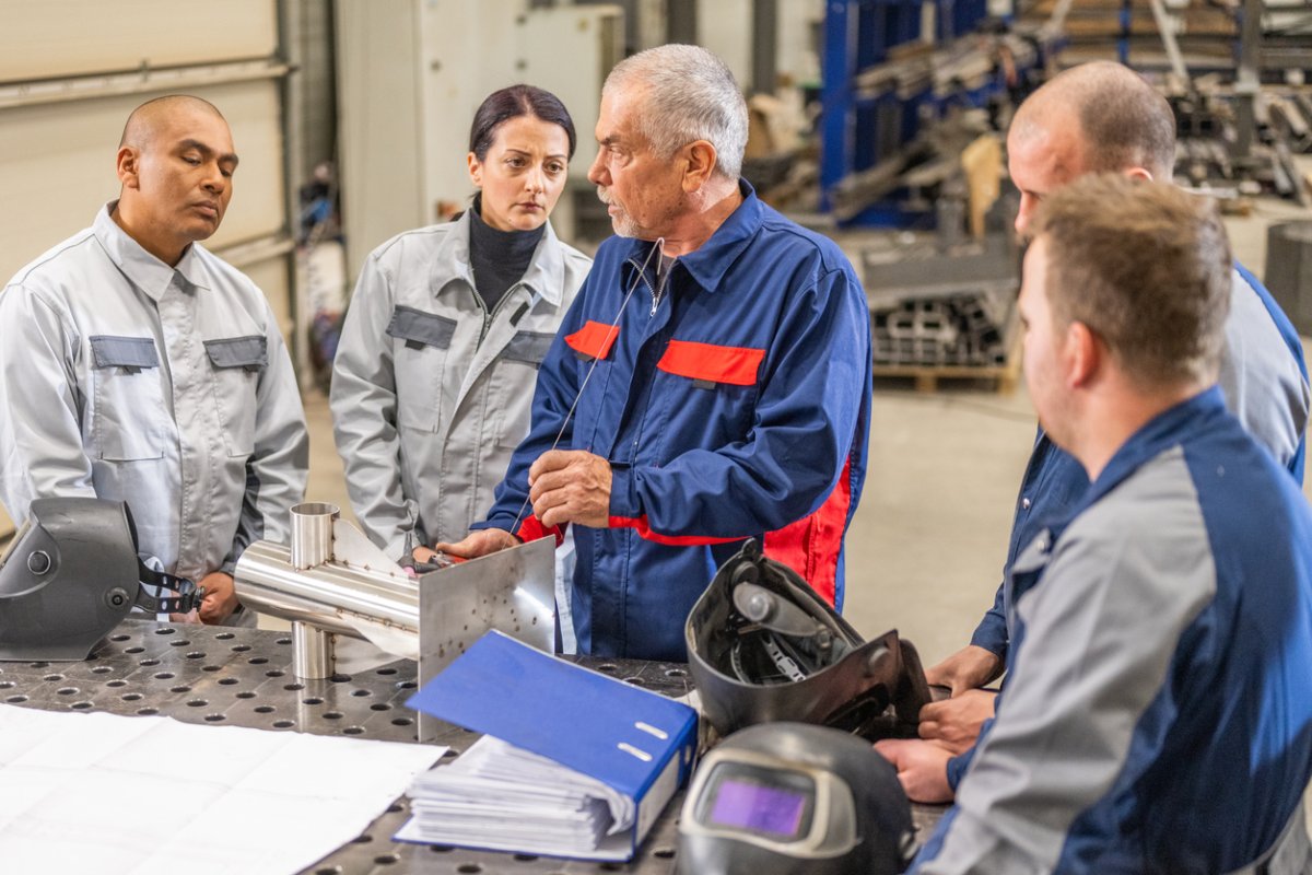 A group of student welders listen to an instructor.