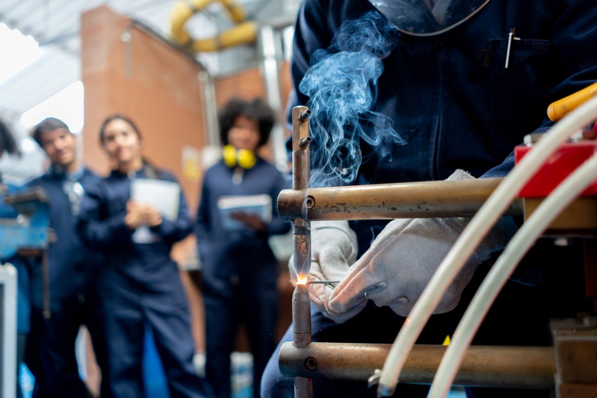 A group of welding students watch a demonstration.