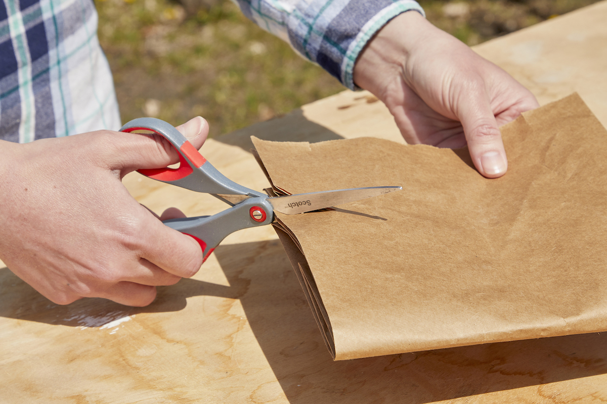 Woman removes burrs from scissor blades by cutting into a paper bag.