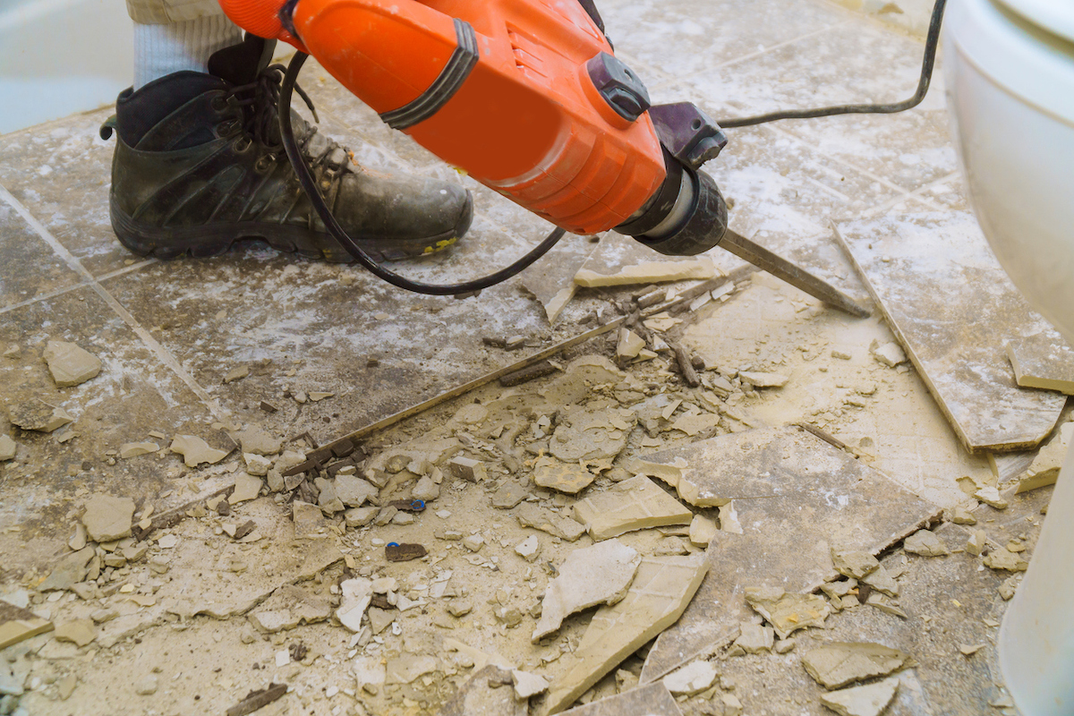 A person is using a jackhammer for a bathroom floor demolition.