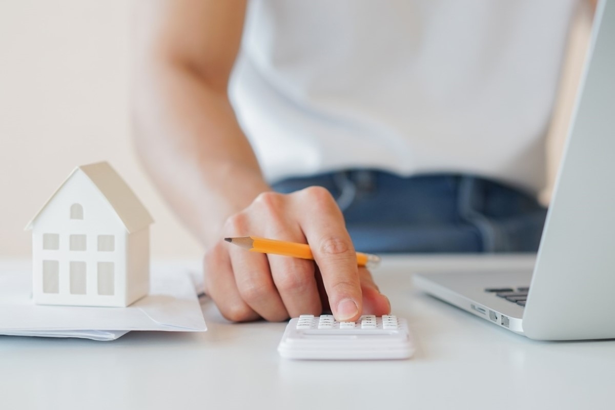 A person is calculating mortgage payments using a calculator and laptop.