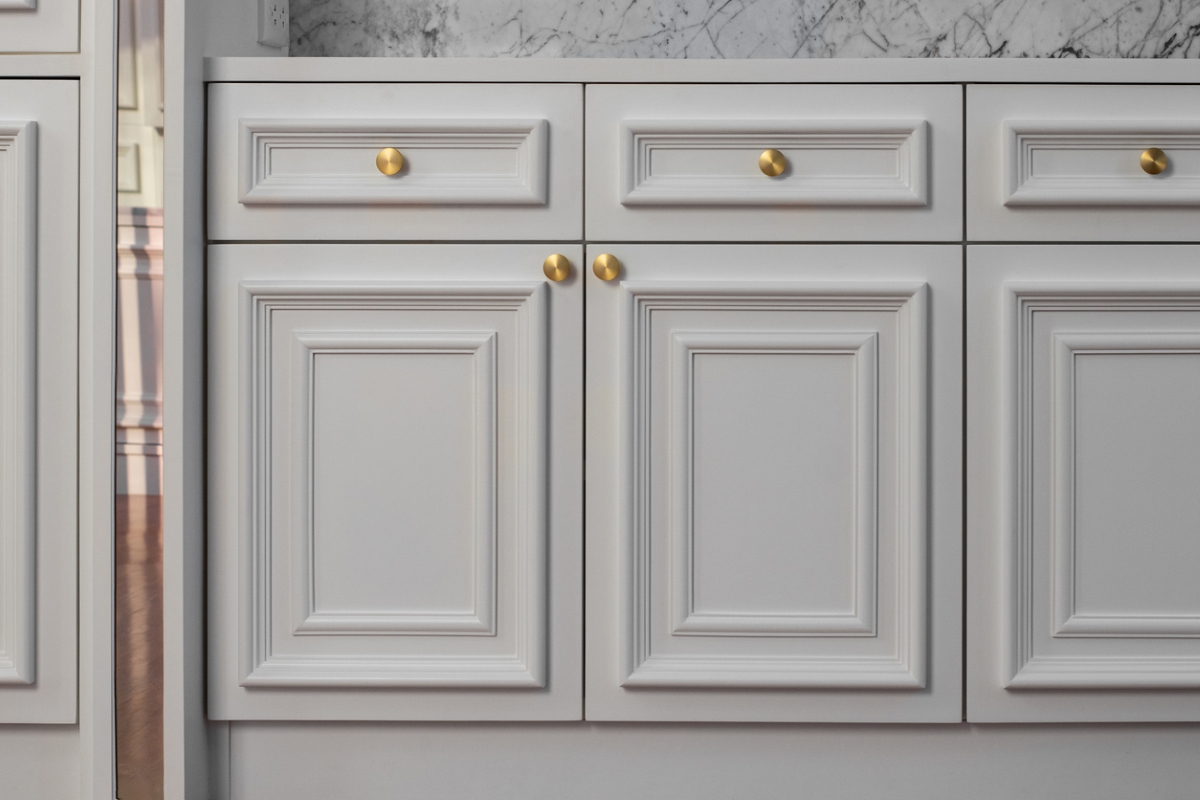 Gray kitchen cabinets with a modern trim around the doors.