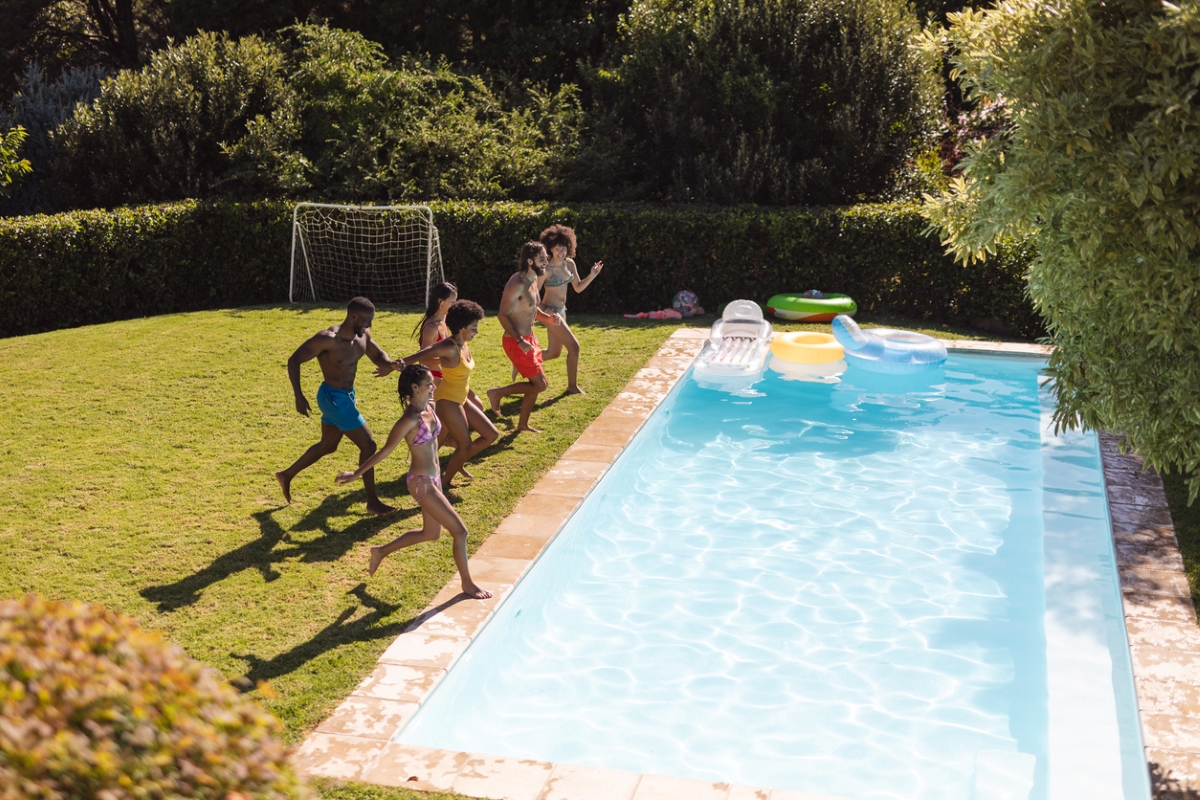 A large group of friends jumping into a pool together.