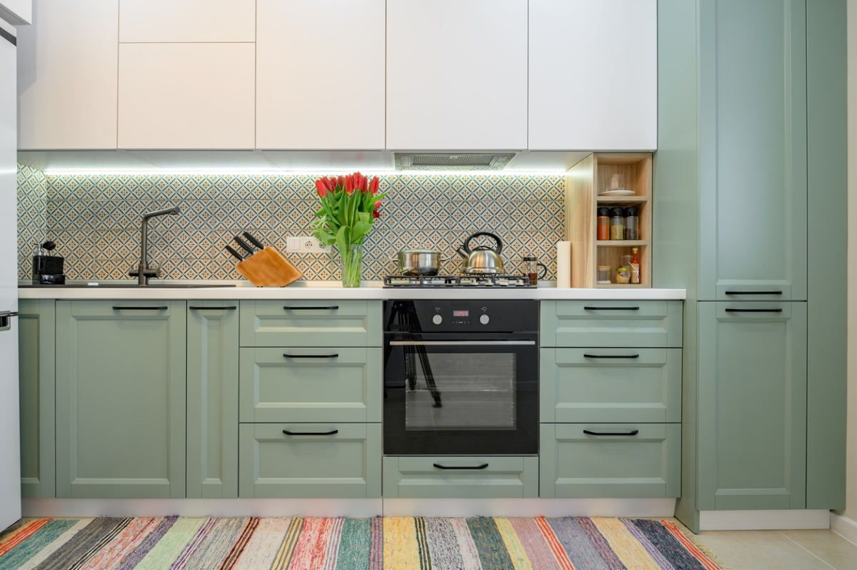 A modern kitchen with green-teal cabinets.