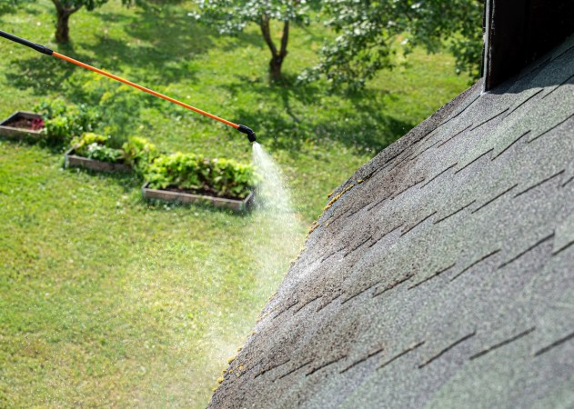 A spray wand cleaning roof shingles on a residential home.