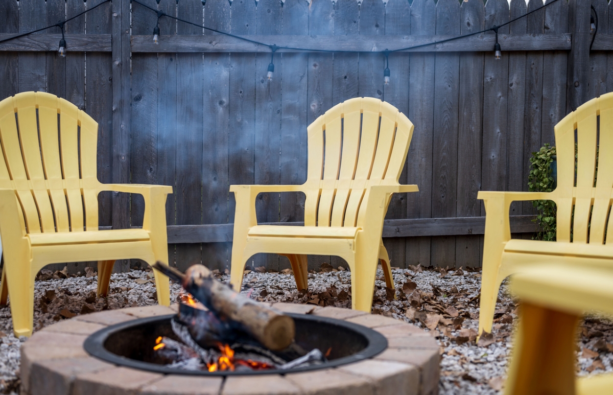 Yellow yard chairs around smoky fire pit.