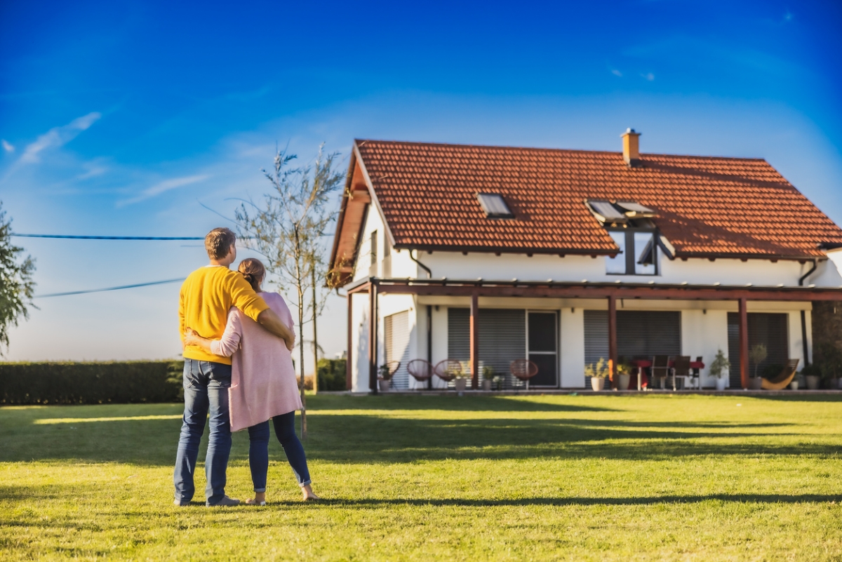 A couple is hugging while looking at their new home.