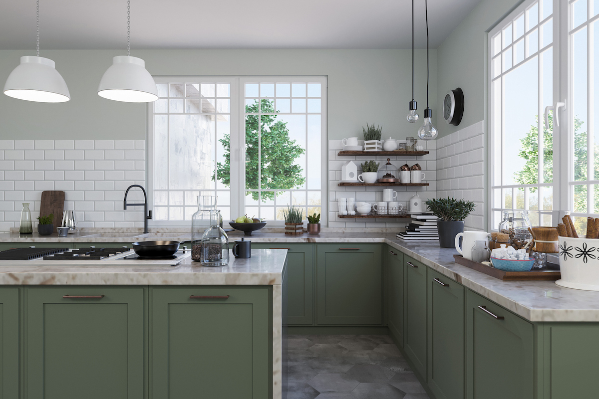 A modern kitchen features sage green cabinetry, open shelving, and white ceramics for decoration.