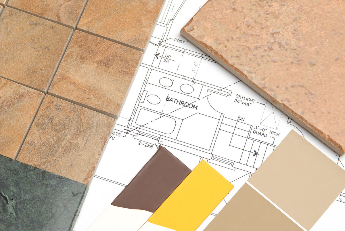 Paint, tile, and counter samples are laying on bathroom design plans.