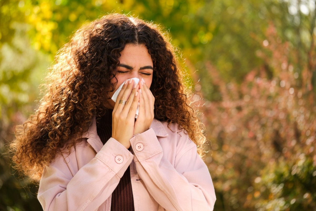 Young woman sneezing into a tissue.