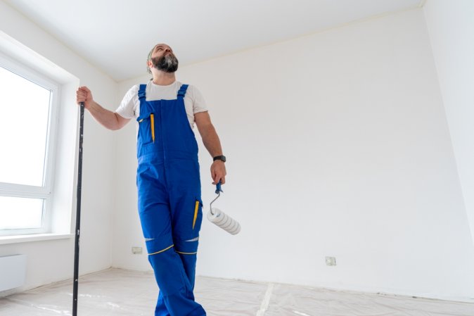 House painter getting ready to paint white walled room.