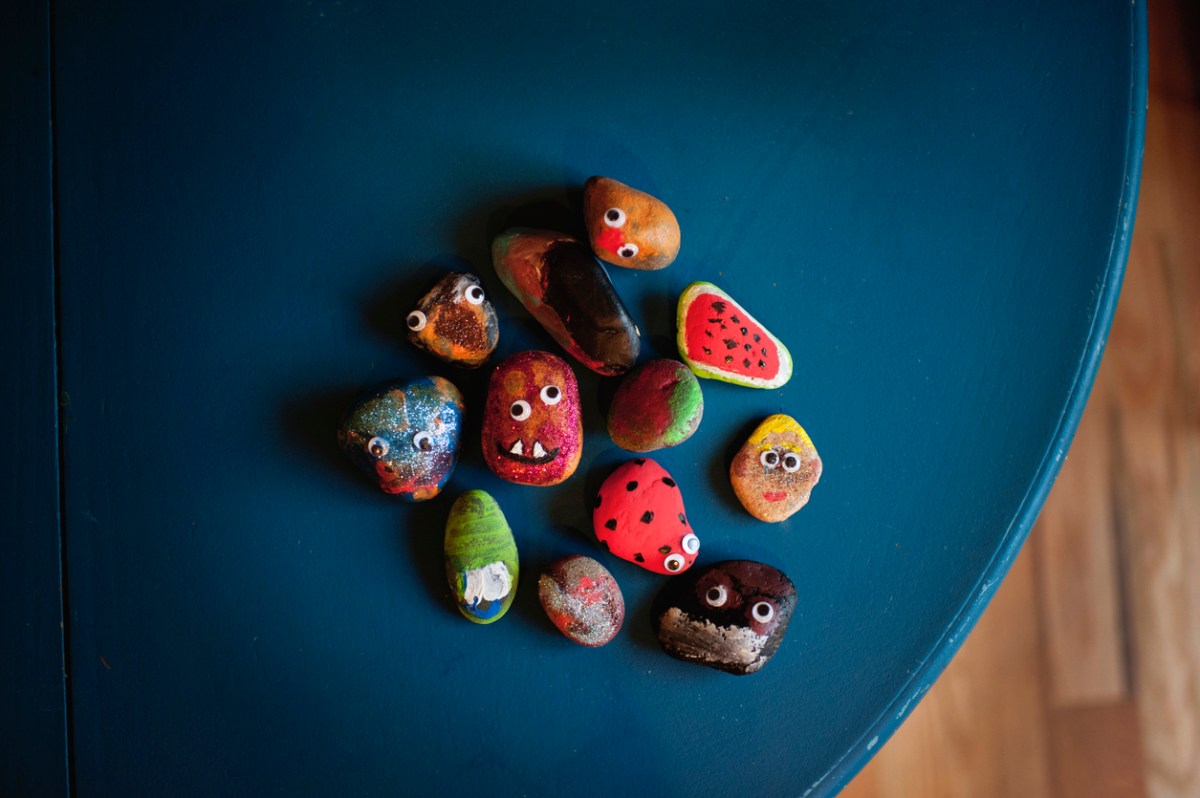 Painted-rocks-with-googly-eyes-sit-on-a-blue-table.