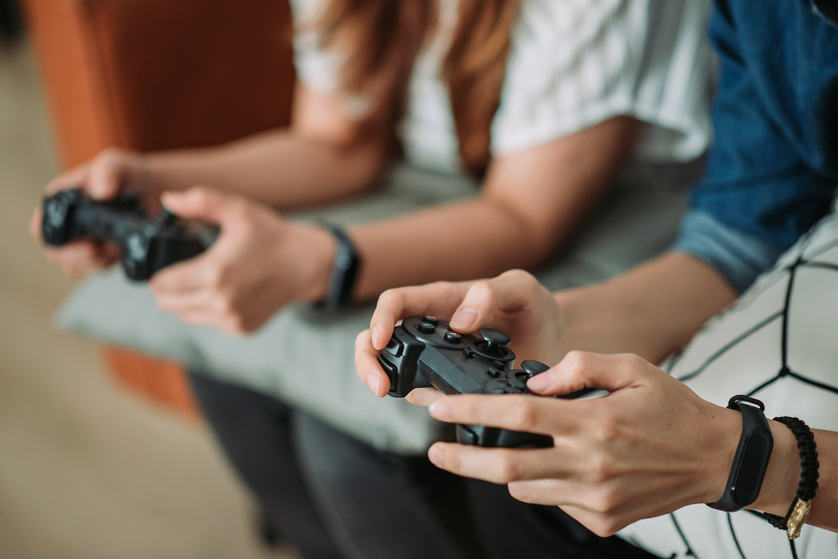 Close up of two young people's hands holding video game controllers.