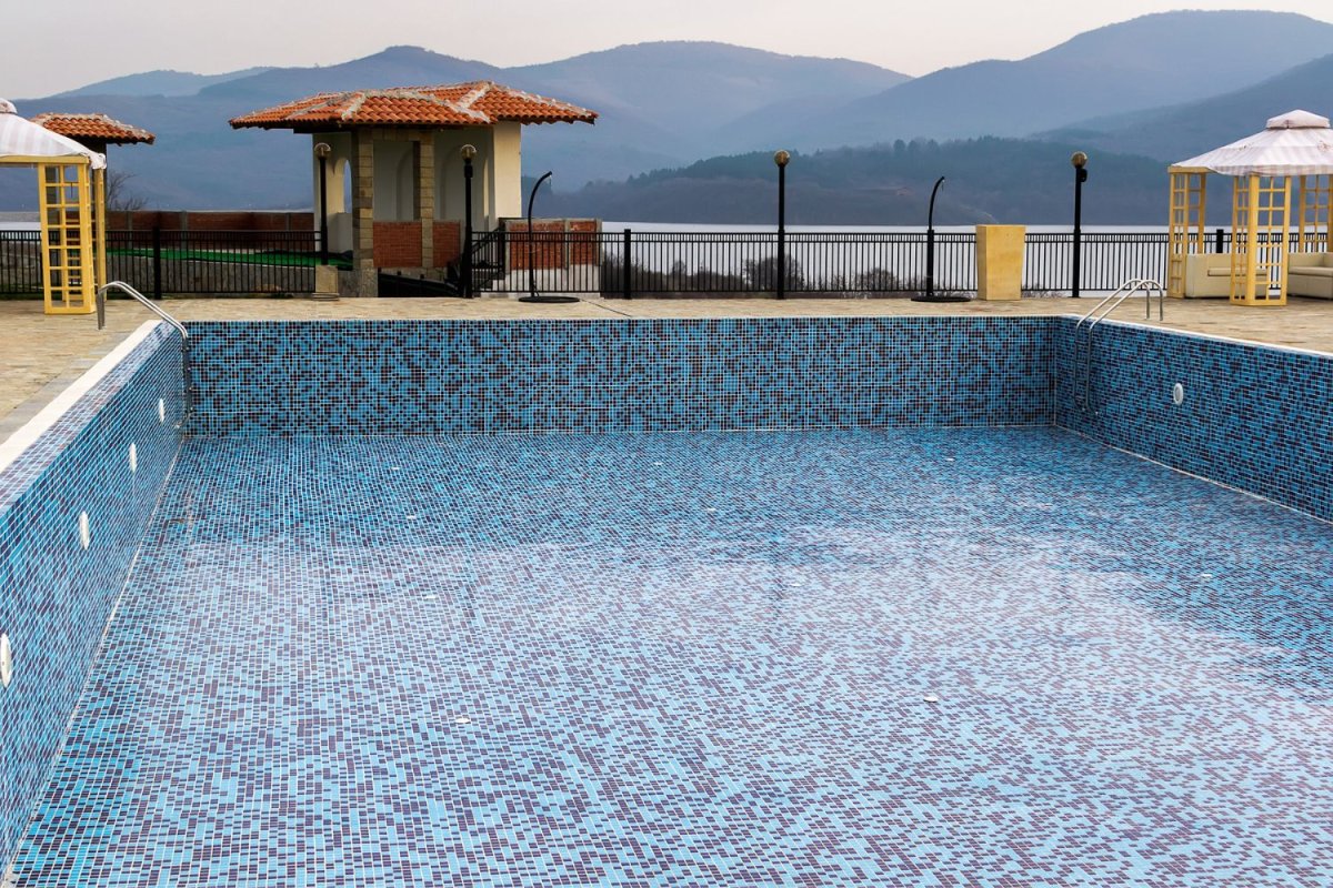 A view of in a in ground pool with a mountain backdrop.