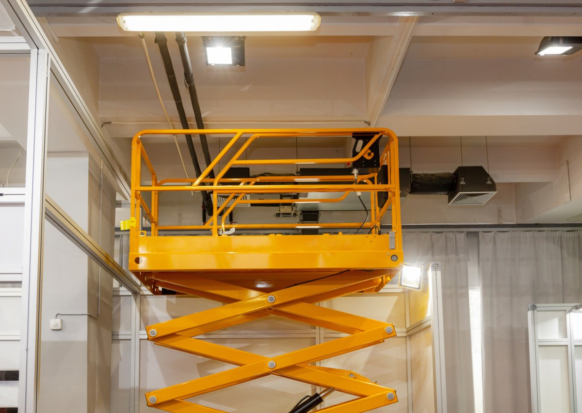 A yellow scissor lift inside a building. 
