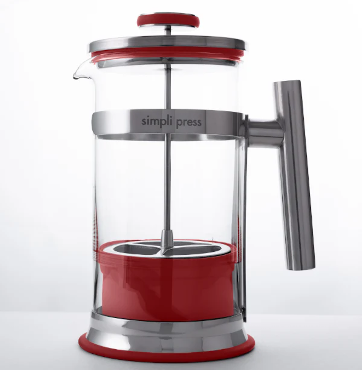A red French press coffee maker sits in front of a white background.
