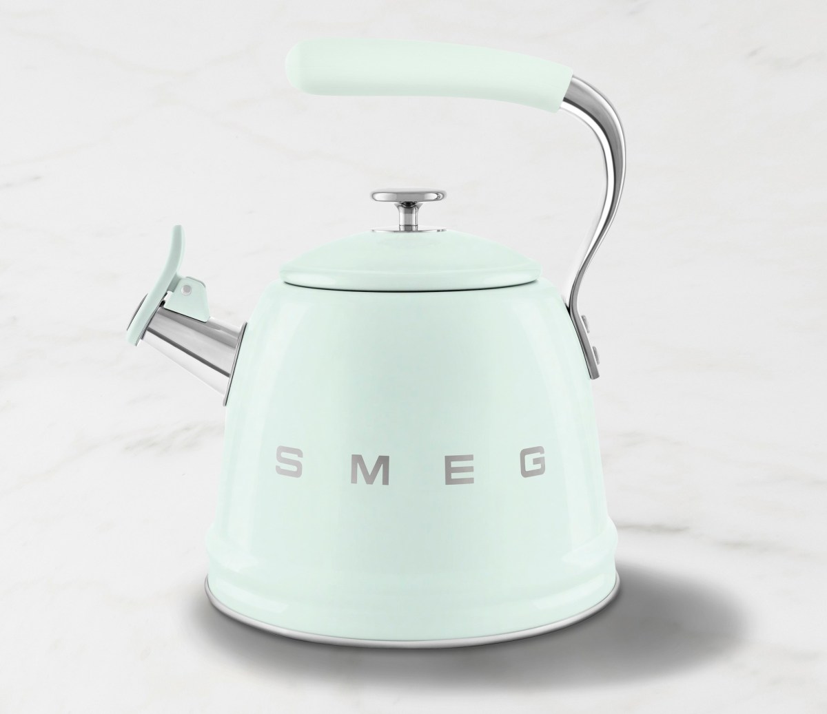 A mint green Smeg tea kettle sits against a white background.