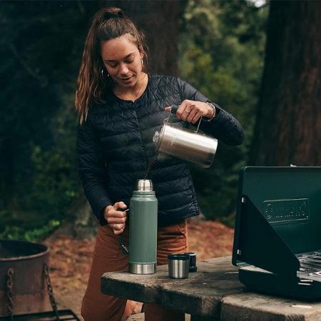 Women pouring beverage into stanley classic thermos.