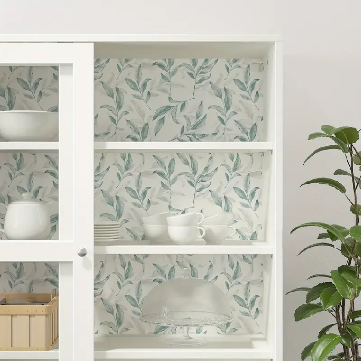 Kitchen cabinet with plant wallpaper lined inside.
