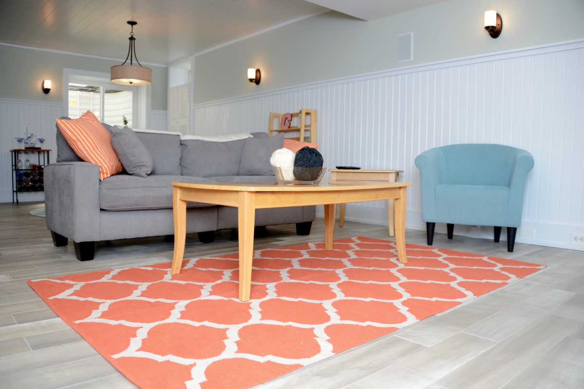 A finished basement with a peach colored rug and couch.
