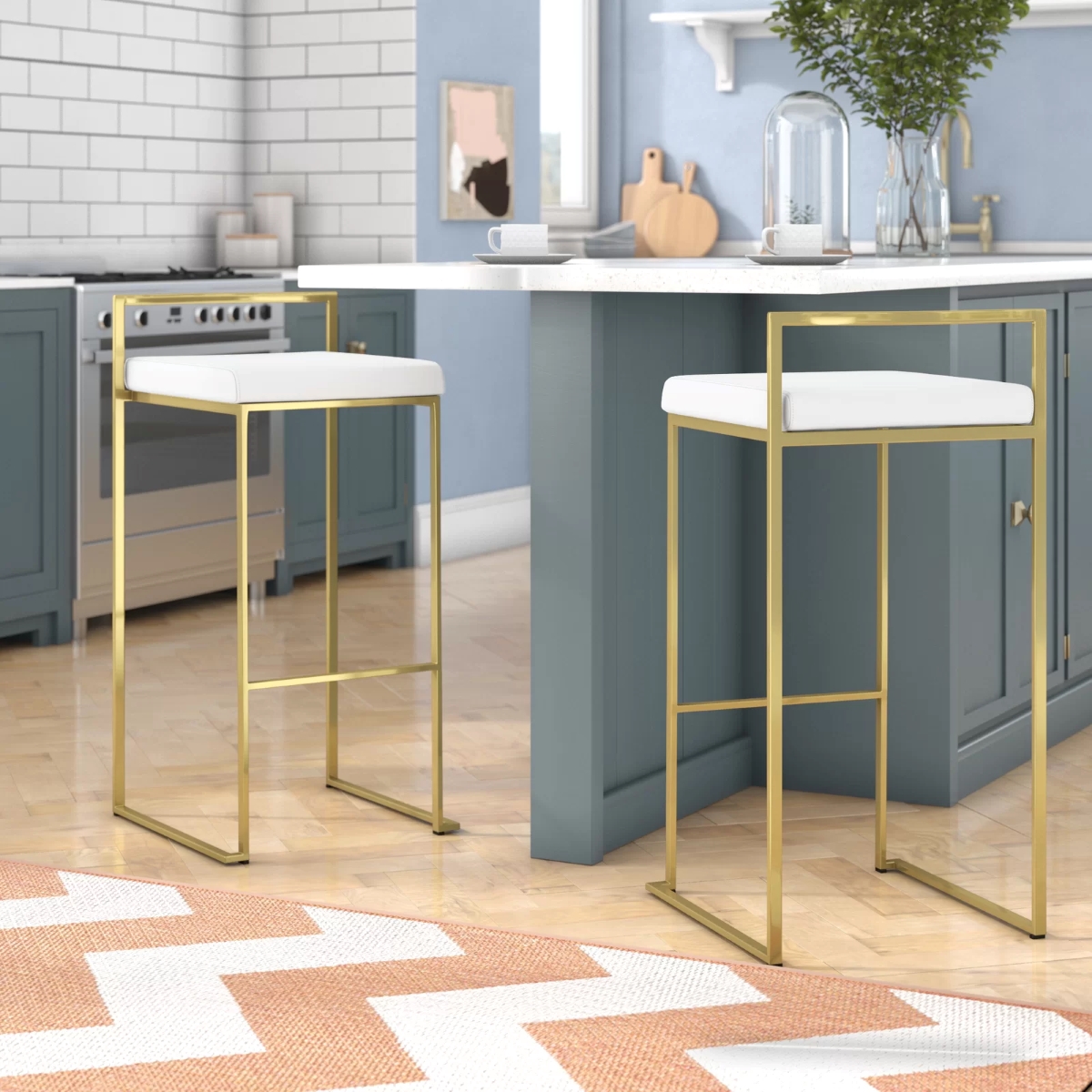 Two kitchen island chairs with white seats and gold metal frames.