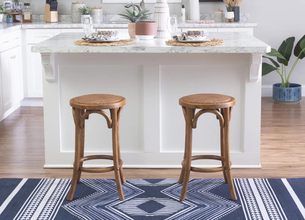 Two counter stools with natural woven fabric seats and wooden frames.
