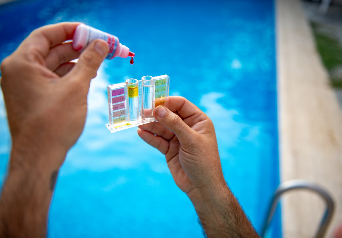 A close up of a person's hands doing a pool water test.