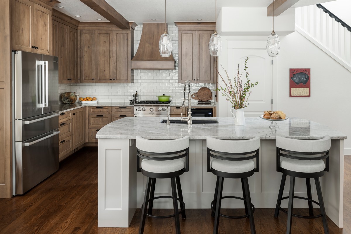 An open concept kitchen with traditional design elements is decorated with wood and neutral colors.