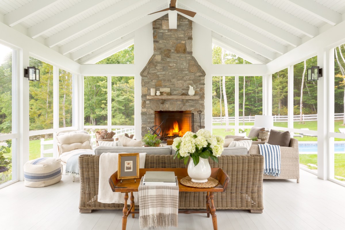 An indoor-outdoor living area has floor-to-ceiling windows and a neutral traditional design style.