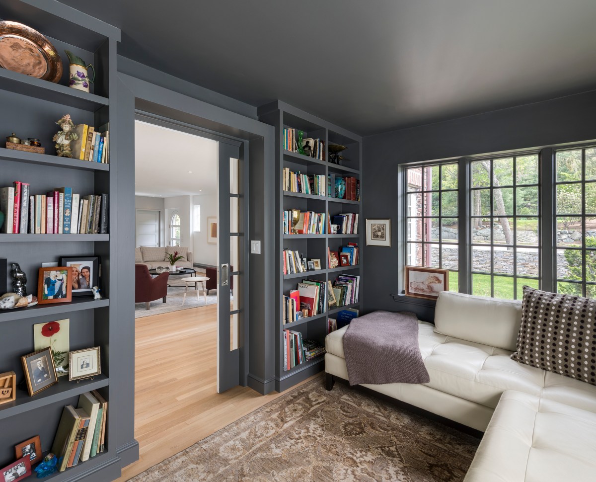 A reading room is decorated with neutral furnishings and grey bookshelves.