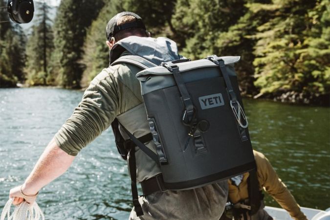 A person wearing the Yeti Hopper M12 Backpack Soft Cooler on a boat.