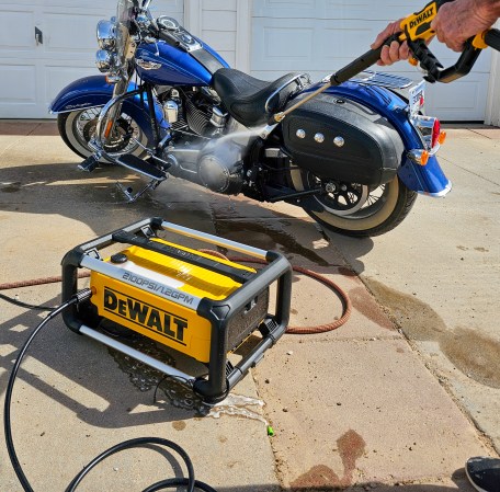 A person using the DeWalt DWPW2100 Electric Jobsite Pressure Washer to clean a motorcycle during testing.