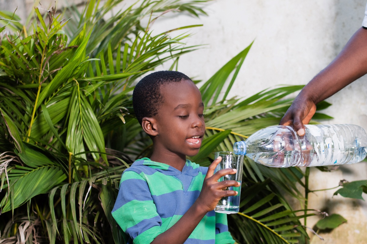 A boy getting a glass of water to drink outside on a hot summer day during the dog days of summer.