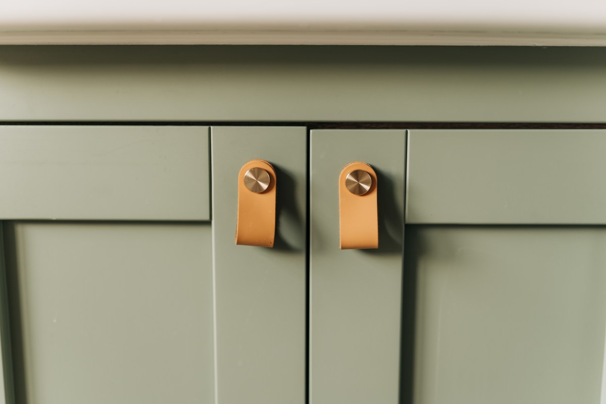 Green cabinets with leather pull handles.