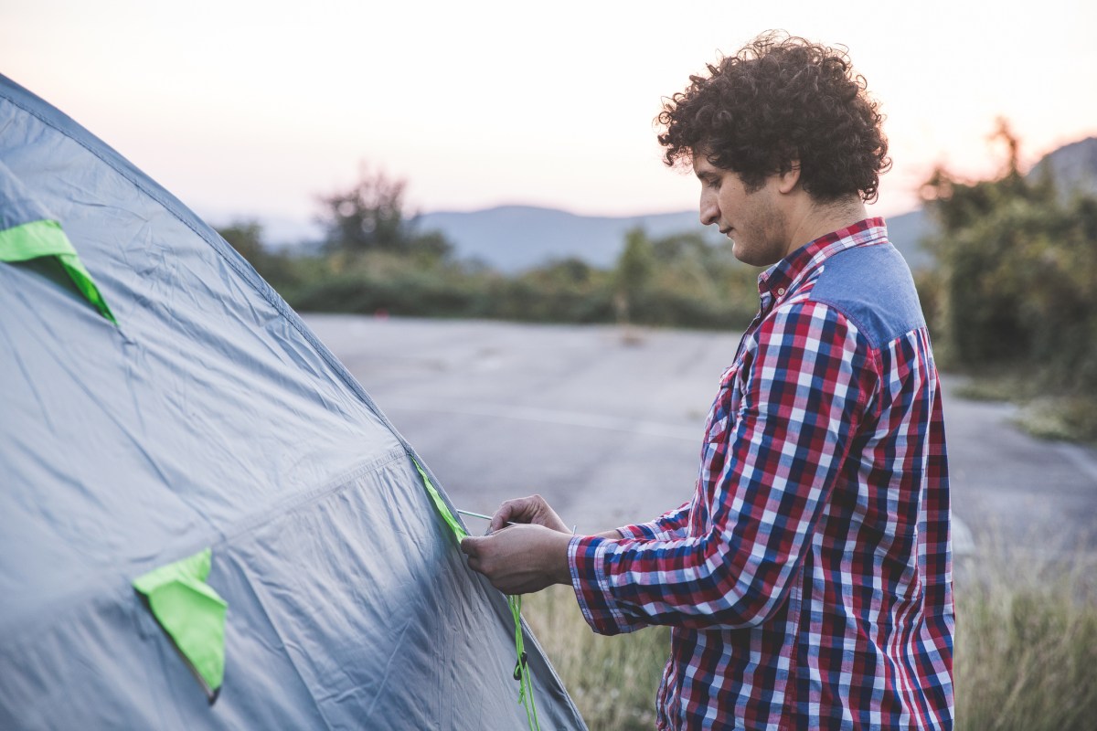 A person ties two flaps of a tent.