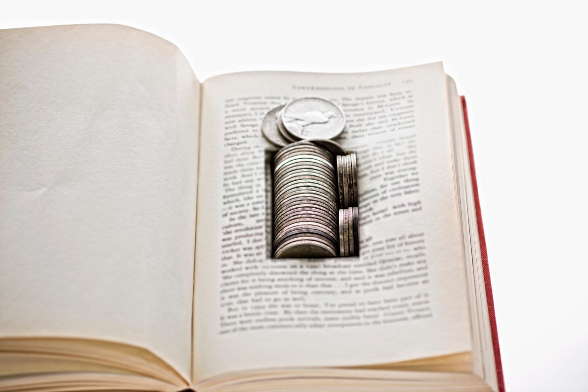 Old silver coins hidden in space cut into the leaves of a book.